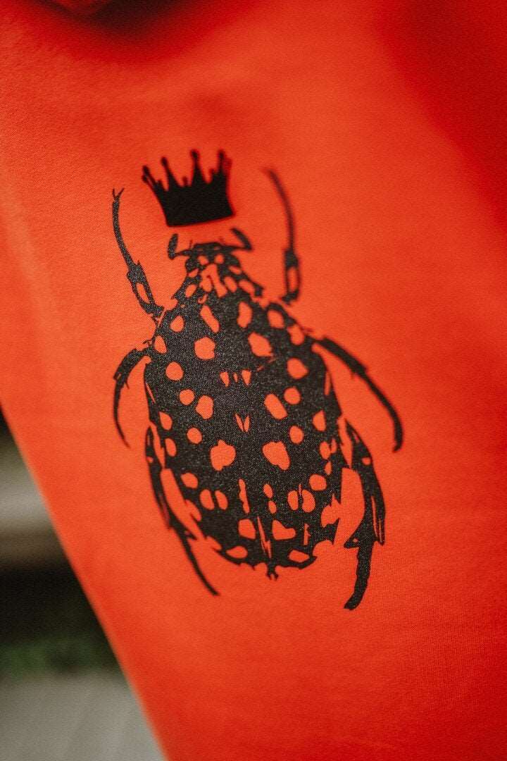 Orangefarbenes Hoodie-Kleid für Damen mit glänzenden schwarzen Käfer auf der Rückseite / Bio-Baumwolle