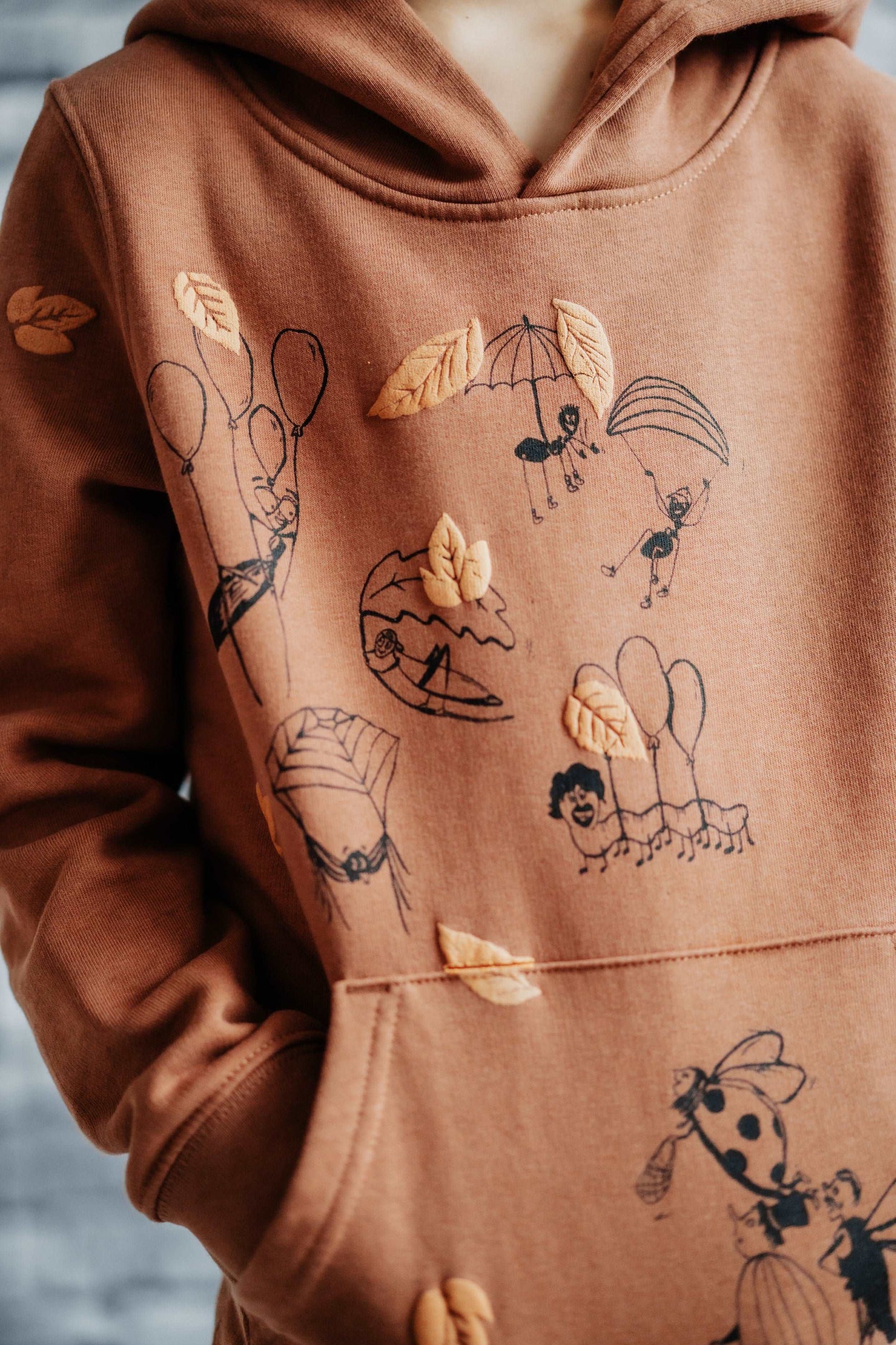 Fallschirmspringer– Zimt-Hoodie mit Frontillustration, Bio-Baumwolle