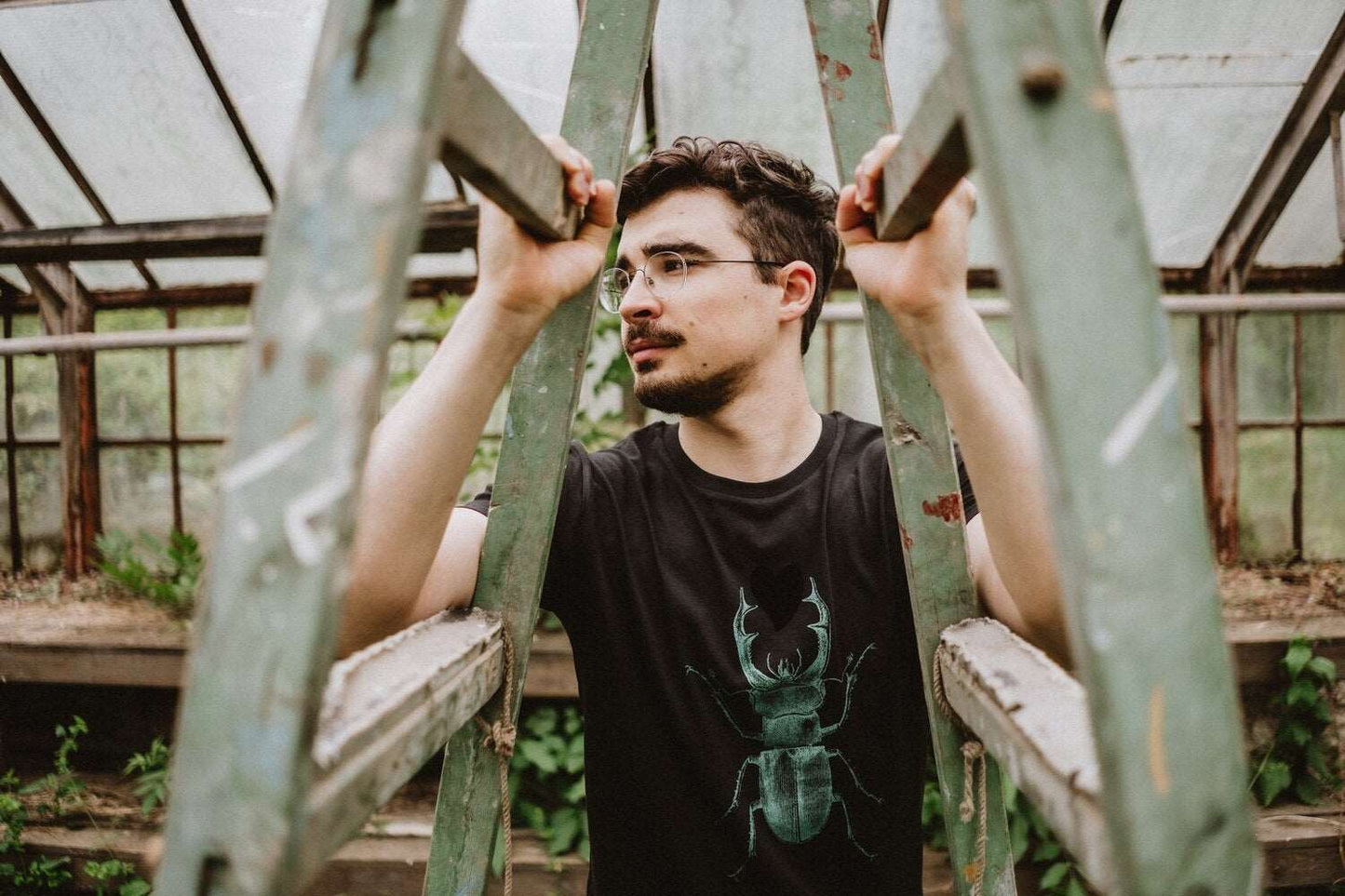 Schwarzes Herren-T-Shirt mit einem grünen Skarabäus, der ein schwarzes Herz hält, 180g Baumwolle