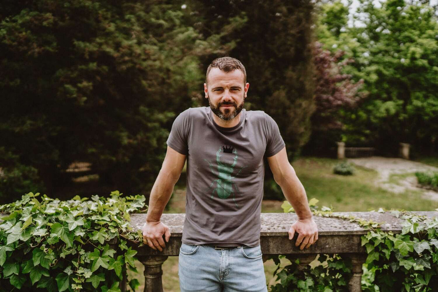 Graues Herren T-Shirt mit grünem Hirschkäfer der eine schwarze Krone hält