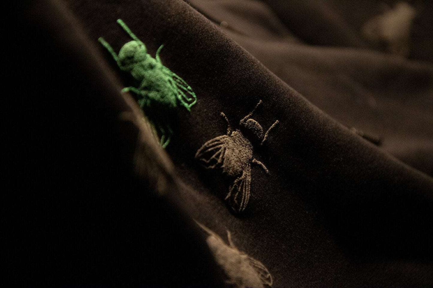 Schwarzer Pullover und 3D-Print einer grauen Fliege, eine grüne ist ebenfalls beteiligt, 350g Bio-Baumwolle